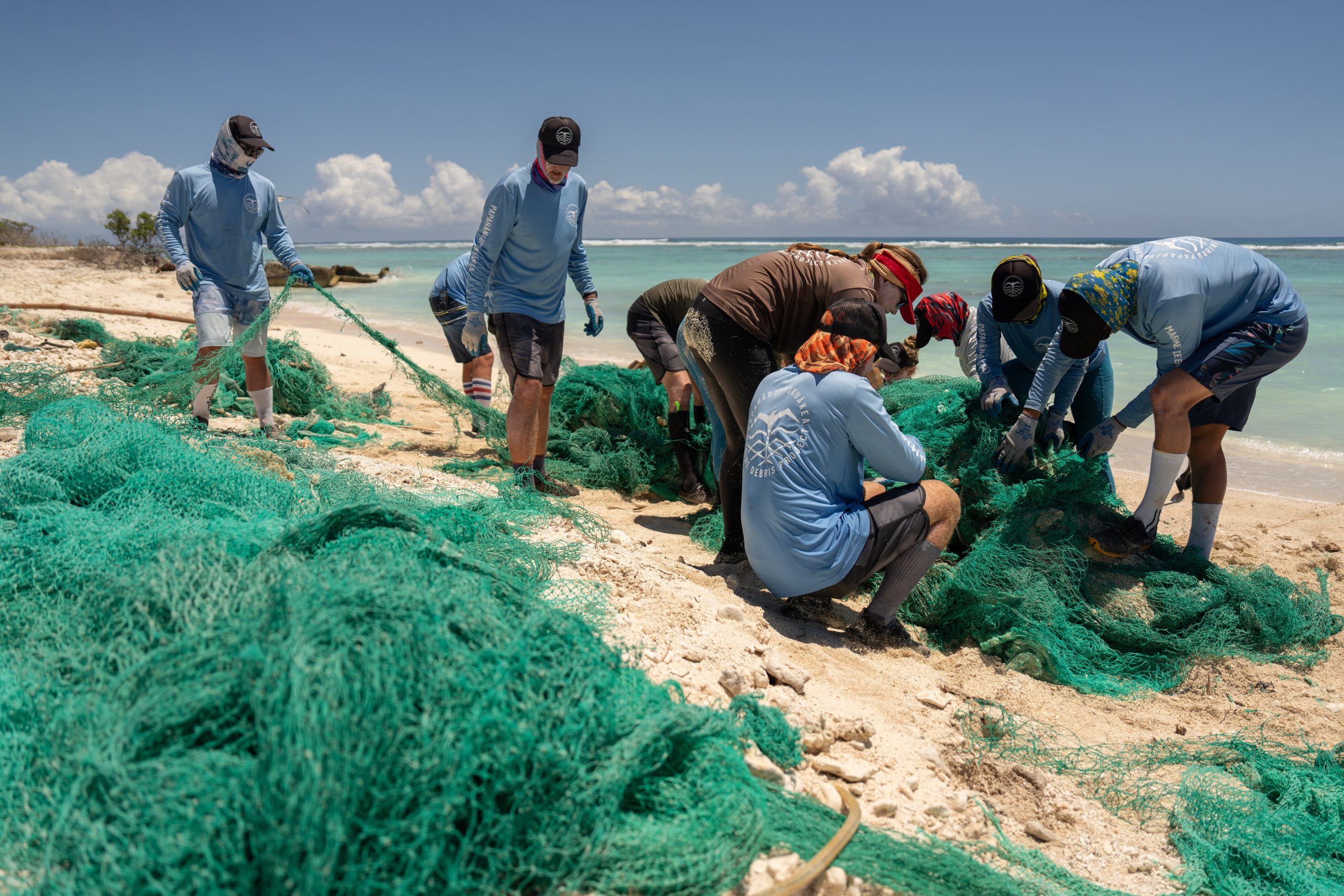 Group of people removing ghost nets from a beach.